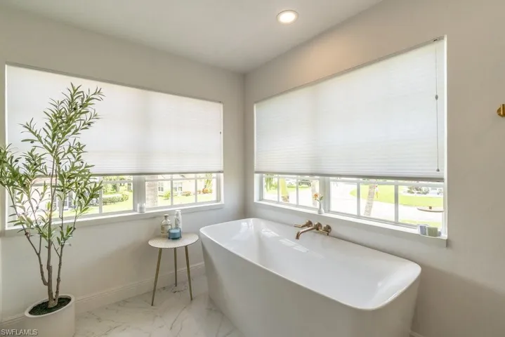 Full bath with a soaking tub, marble finish flooring, and recessed lighting