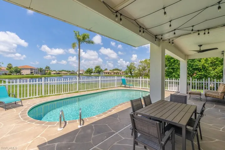View of pool featuring a patio, a fenced backyard, a water view, and ceiling fan
