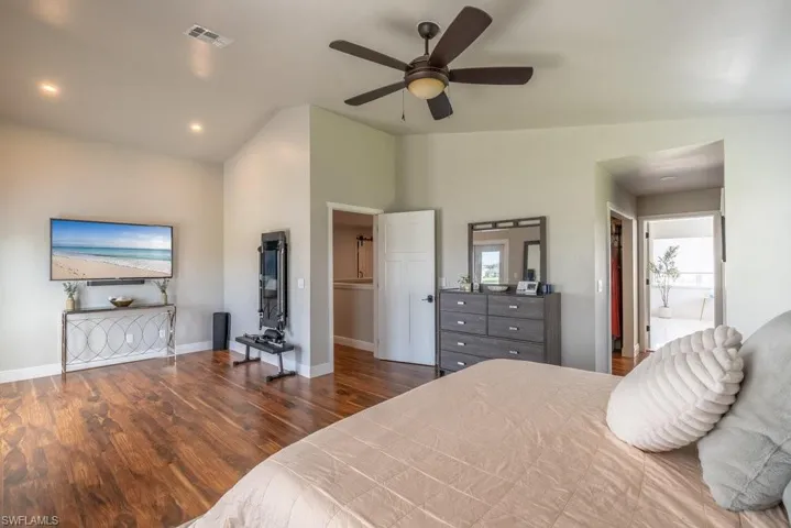 Bedroom featuring vaulted ceiling, wood finished floors, recessed lighting, ceiling fan, and connected bathroom