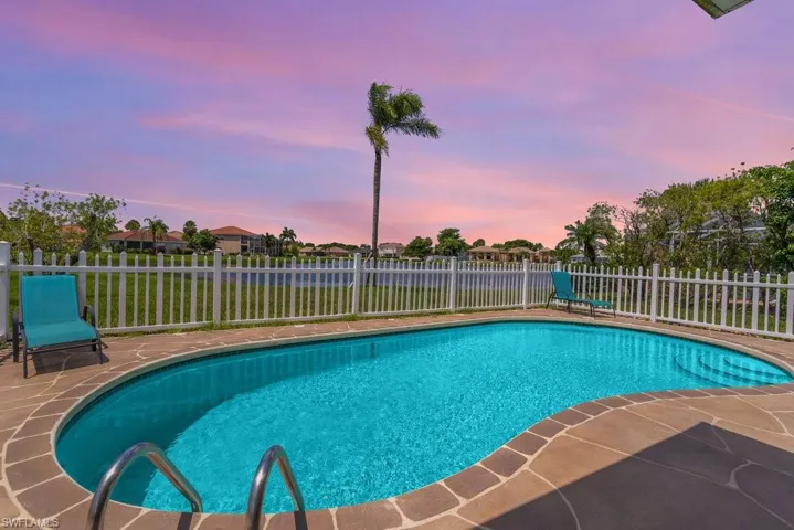 Pool at dusk with a fenced backyard and a patio area