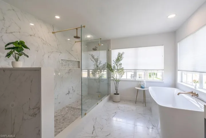Bathroom featuring a marble finish shower, a freestanding bath, recessed lighting, and marble tiled floors