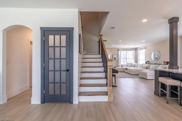 Stairway with wood finished floors, arched walkways, and recessed lighting