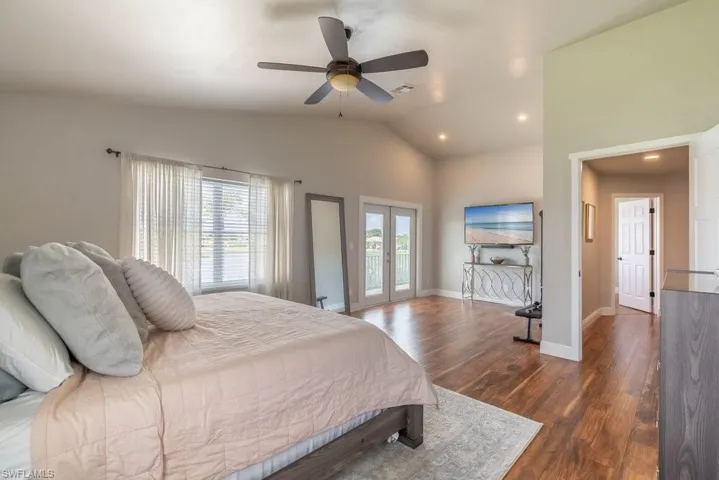 Bedroom featuring access to exterior, dark wood finished floors, lofted ceiling, a ceiling fan, and recessed lighting