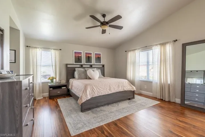 Bedroom with vaulted ceiling, dark wood-style floors, and ceiling fan