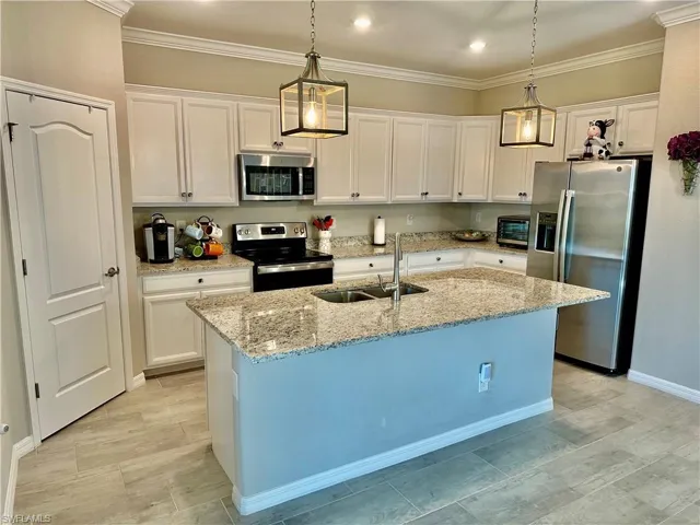 Kitchen with a kitchen island with sink, sink, pendant lighting, and stainless steel appliances
