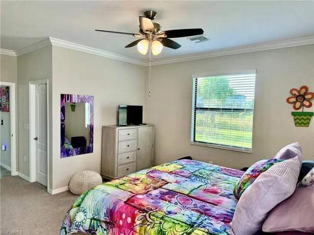 Carpeted bedroom featuring crown molding and ceiling fan