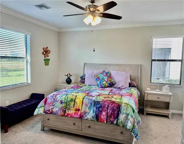 Carpeted bedroom featuring ornamental molding and ceiling fan