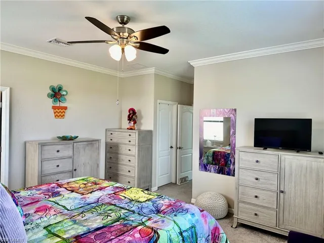 Carpeted bedroom with crown molding and ceiling fan