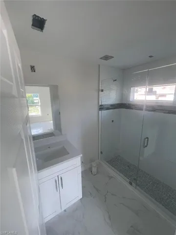 Bathroom with tile flooring, a shower with shower door, and vanity