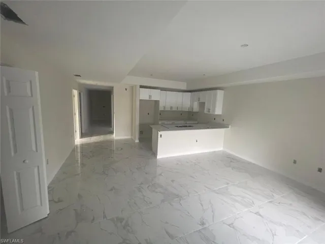 Unfurnished living room featuring sink and light tile floors