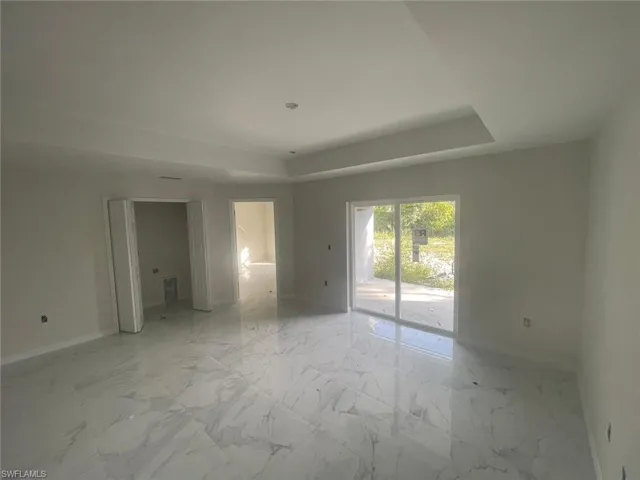 Spare room with a tray ceiling and light tile floors