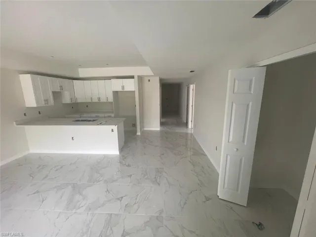 Kitchen with sink, white cabinets, kitchen peninsula, and light tile floors
