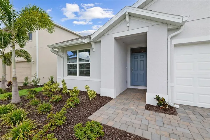 Contemporary exterior featuring a panel-paneled entry door, paver walkway, and attached garage