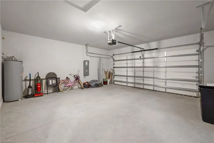 Spacious two-car garage with a concrete floor, white walls, and an overhead garage door opener