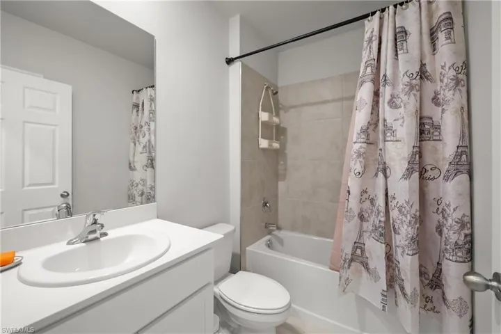 Guest bath between bedrooms Bathroom featuring a white vanity with an integrated sink, chrome faucet, and a large wall-mounted mirror
