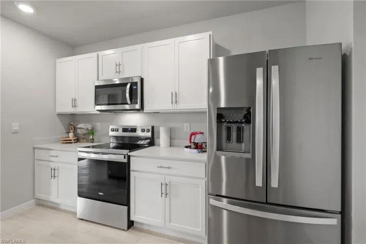 Modern kitchen featuring white cabinetry, light-toned countertops, stainless steel appliances, and recessed lighting