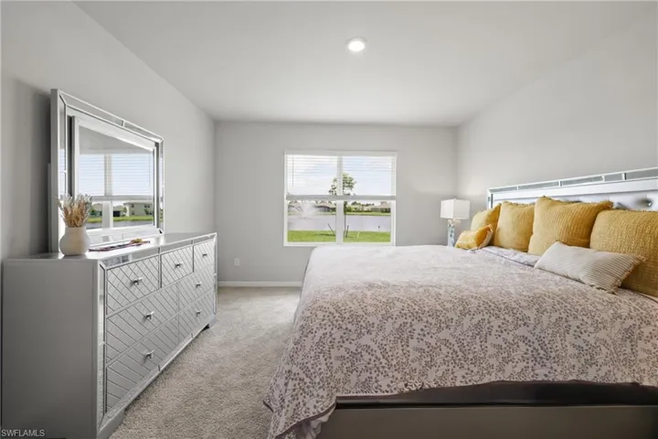 Spacious bedroom featuring light neutral wall paint, recessed lighting, and soft carpet flooring