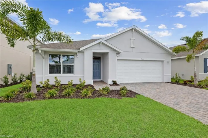 Contemporary single-story residence featuring a two-car garage, paver driveway, and a welcoming front entrance with a blue door