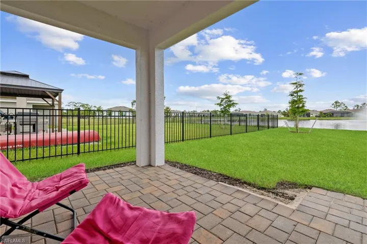 Covered patio with paver flooring overlooking a fenced yard and water feature
