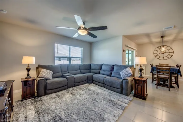Spacious living room filled with natural sunlight, tile floor, and upgraded ceiling fan
