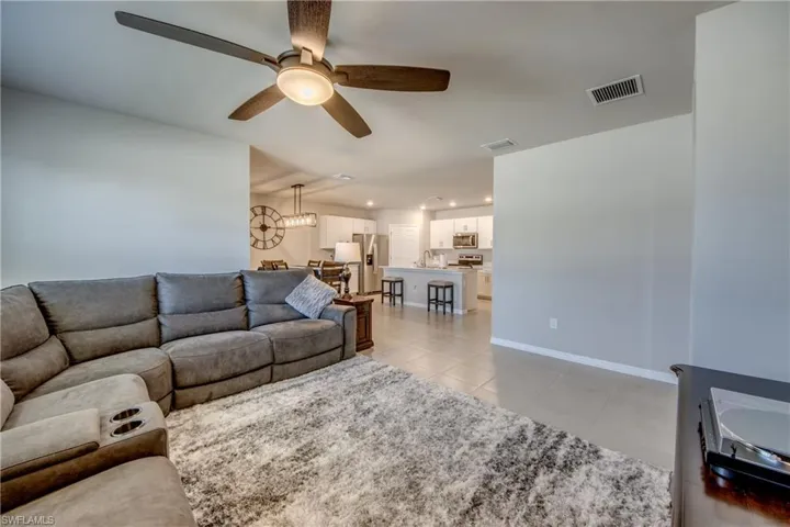 Spacious living room filled with natural sunlight, tile floor, and upgraded ceiling fan