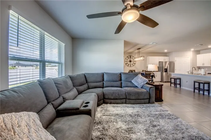 Spacious living room filled with natural sunlight, tile floor, and upgraded ceiling fan