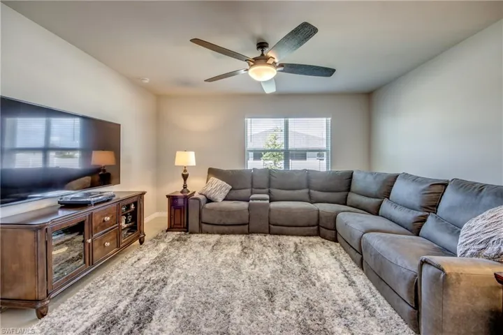 Spacious living room filled with natural sunlight, tile floor, and upgraded ceiling fan