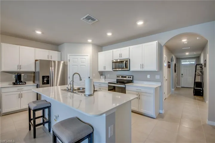Kitchen featuring a large island, stainless steel appliances, quartz counters and designer cabinets
