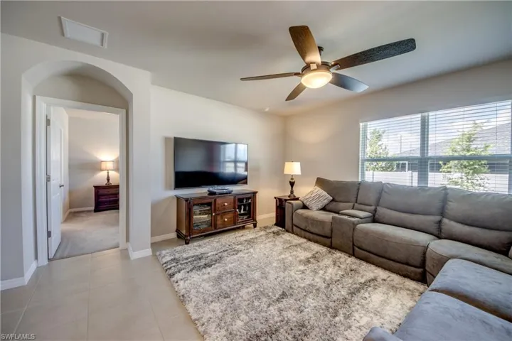 Spacious living room filled with natural sunlight, tile floor, and upgraded ceiling fan