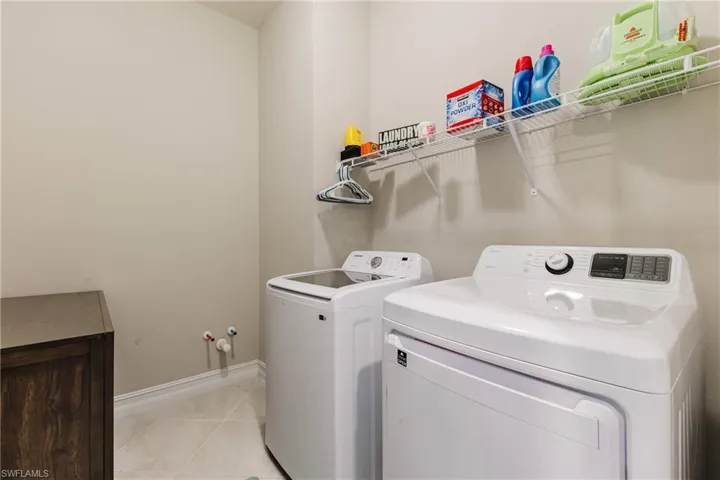 Laundry room featuring light tile patterned floors and washing machine and dryer