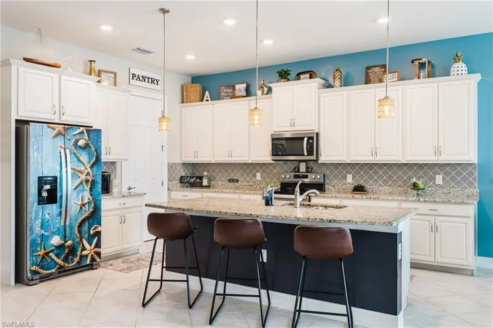 Kitchen with light tile patterned floors, appliances with stainless steel finishes, hanging light fixtures, and recessed lighting