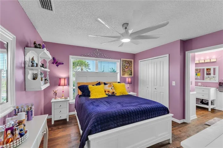 Bedroom featuring a textured ceiling, ceiling fan, dark wood-type flooring, and a closet