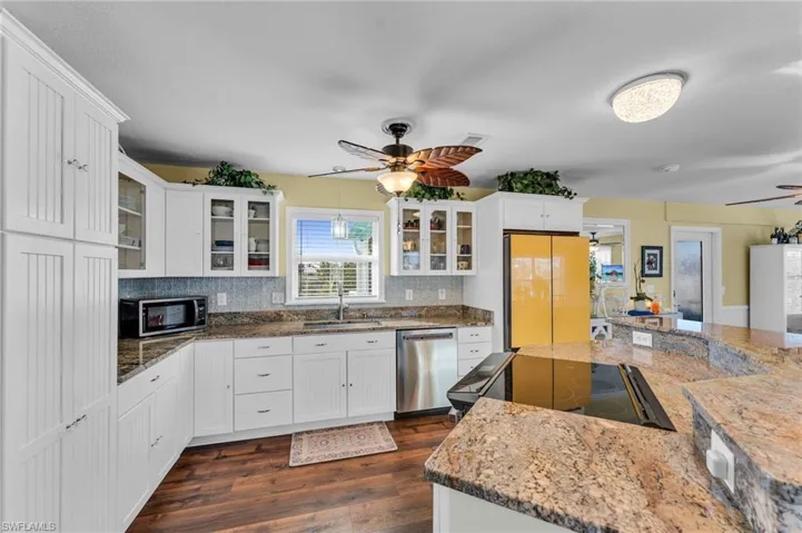 Kitchen with sink, light stone counters, decorative backsplash, white cabinets, and appliances with stainless steel finishes