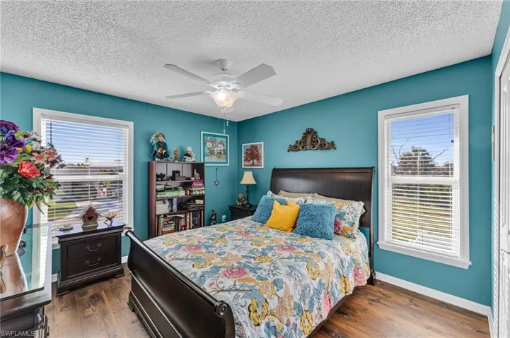 Bedroom featuring a closet, a textured ceiling, dark hardwood / wood-style floors, and ceiling fan
