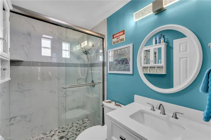 Bathroom with vanity, toilet, and a shower with door