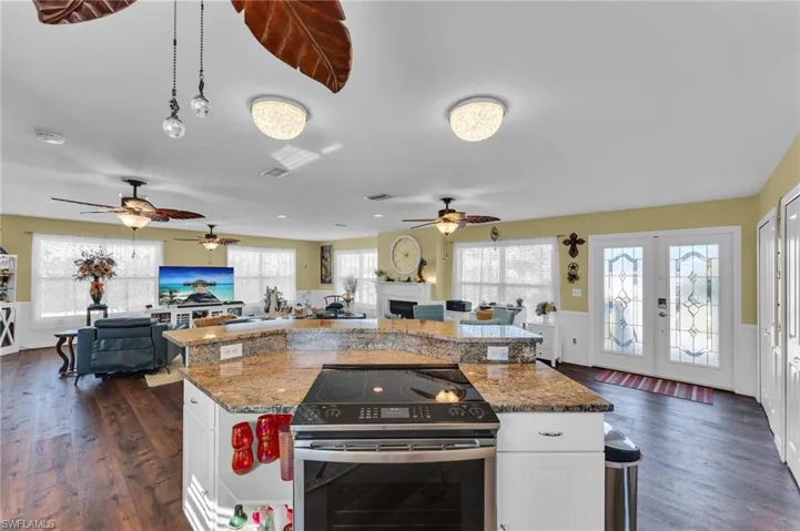 Kitchen with white cabinetry, stainless steel electric range oven, a kitchen island, and stone countertops