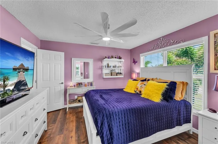 Bedroom with a textured ceiling, ceiling fan, and dark wood-type flooring