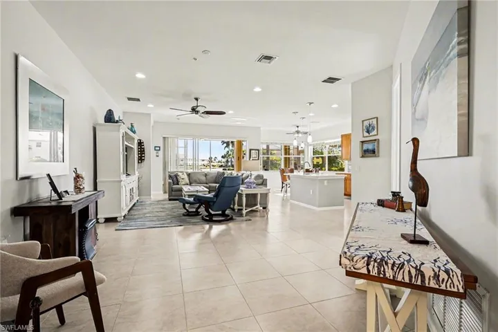 Spacious living area featuring large neutral tile floors and recessed lighting.