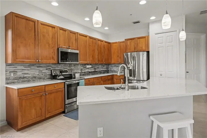 Modern, fresh kitchen with updated lighting, appliances and beautiful quart countertops.