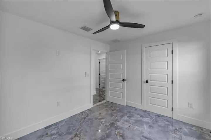 Unfurnished bedroom with marble tiled floors, a closet, and a ceiling fan