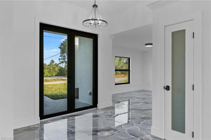 Entrance foyer with light marble finish flooring and a chandelier