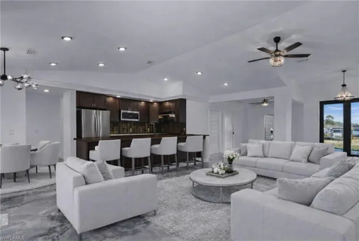 Living area with a chandelier, marble tiled floors, lofted ceiling, ceiling fan, and recessed lighting