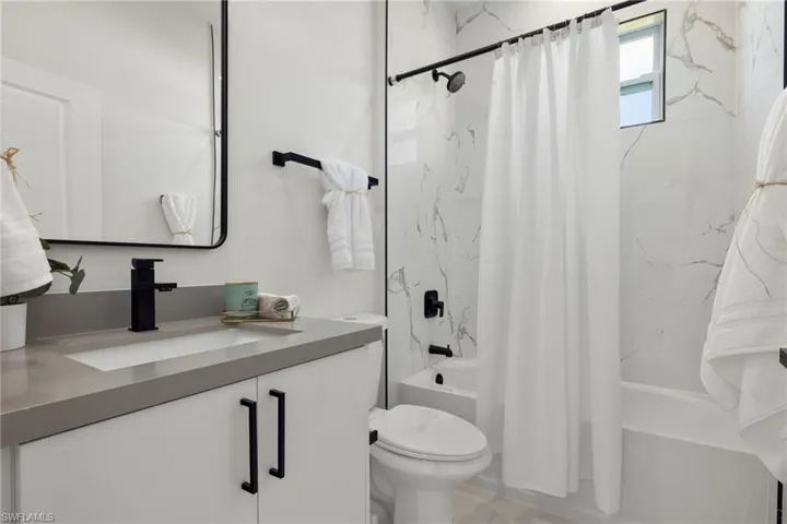 Full bathroom with vanity, shower / tub combo, and toilet