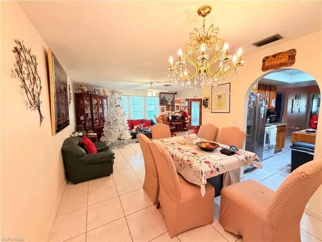 Dining area featuring arched walkways, light tile patterned floors, hanging lights, and ceiling fan