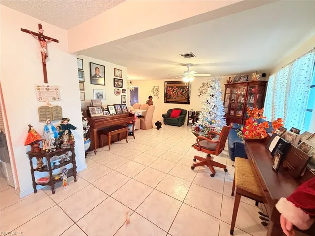 Living area with ceiling fan, a textured ceiling, and light tile patterned floors
