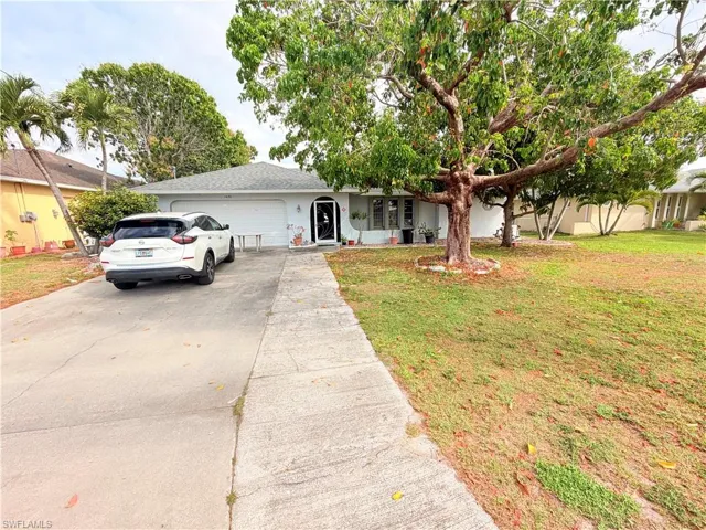 Ranch-style house with concrete driveway, an attached garage, and a front yard