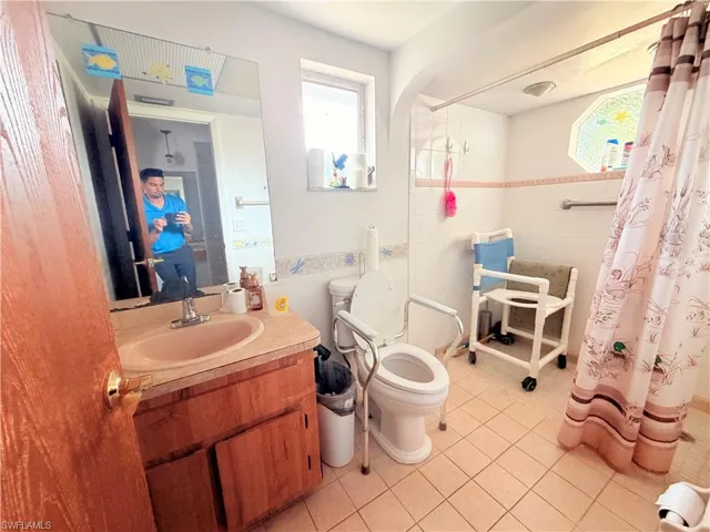 Bathroom with a tile shower, vanity, plenty of natural light, and light tile patterned floors