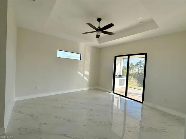 Master bedroom with canal view, tile flooring, a tray ceiling, and ceiling fan.