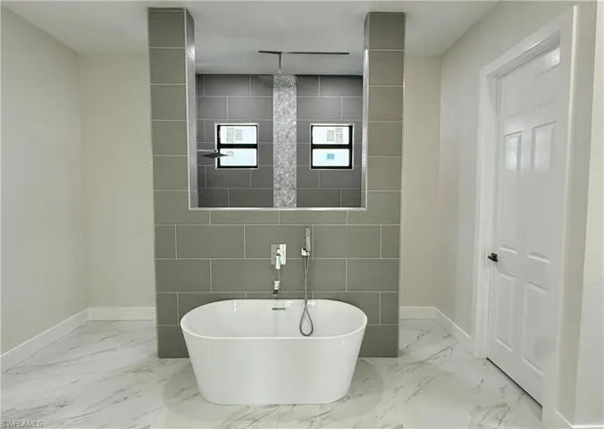 Bathroom with a freestanding tub and light marble finish flooring