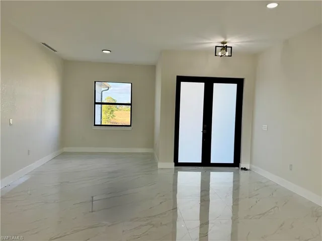 Flex room with light marble finish flooring, recessed lighting, and french doors